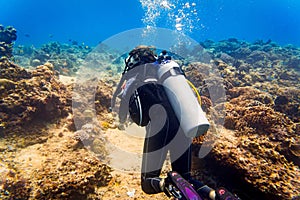 Woman diver at tropical coral reef scuba diving in tropical ocean