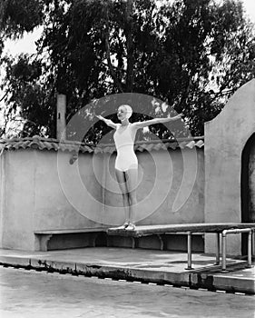 Woman on diving board at swimming pool