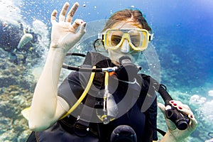 Woman diving on coral reef giving the ok sign