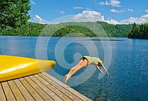 Woman diving off the dock into lake on a hot summer day