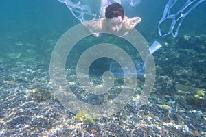 Woman diving in the sea with garbage