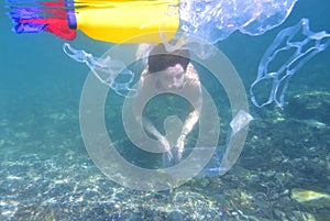 Woman diving in the sea with garbage, plastic