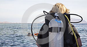 Woman in diving suit with aqualung ready to dive into sea