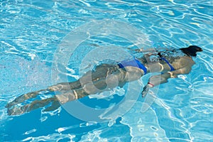 Woman diving in the swimming pool. Young beautiful girl swimming in pool. Brunette relaxing in clear warm water on sunny day. Top