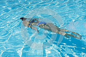 Woman diving in the swimming pool. Young beautiful girl swimming in pool. Brunette relaxing in clear warm water on sunny day. Top