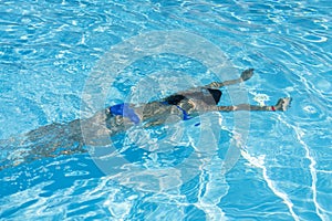 Woman diving in the swimming pool. Young beautiful girl swimming in pool. Brunette relaxing in clear warm water on sunny day. Top