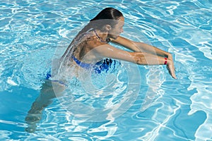 Woman diving in the swimming pool. Young beautiful girl swimming in pool. Brunette relaxing in clear warm water on sunny day. Top