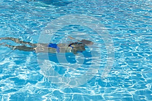 Woman diving in the swimming pool. Young beautiful girl swimming in pool. Brunette relaxing in clear warm water on sunny day. Top