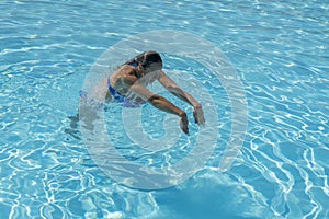 Woman diving in the swimming pool. Young beautiful girl swimming in pool. Brunette relaxing in clear warm water on sunny day. Top