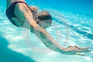 Woman diving underwater with goggles in swimming pool