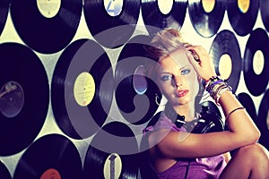Woman, dj and portrait in record studio with headphones at rave party, sitting and wall of vinyls for music event photo