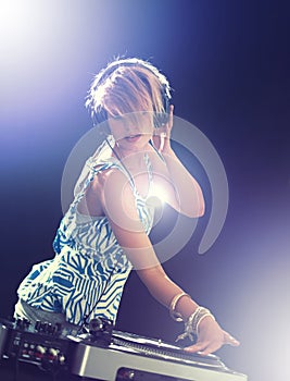 Woman, dj and turntable with headphones for mixing on stage for concert, music and gig at rave party for entertainment