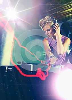 Woman, dj and turntable with headphones for music on stage with lens flare, mixing and gig at rave party for