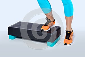 Woman do exercise on a black-turquoise fitness step