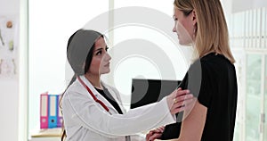 Woman doctor attentively consoles doctor patient holding hands in gynecologist office