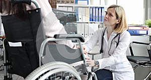 Woman doctor comforts a patient with x-ray in wheelchair