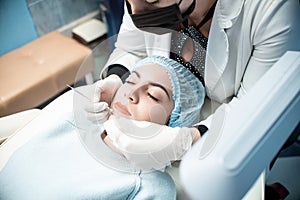 Woman doctor conducts a medical procedure to clean the face of a young girl