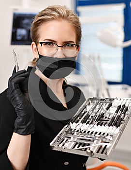 Woman doctor dentist surgeon with medical tools standing in dental