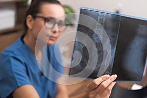 Woman doctor examines X-ray images of pelvis carefully looking for cause of patient complaints