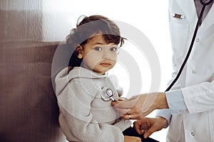 Woman-doctor examining a child patient by stethoscope. Cute arab toddler at physician appointment. Medicine concept