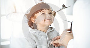 Woman-doctor examining a child patient by stethoscope in sunny clinik. Cute arab toddler at physician appointment