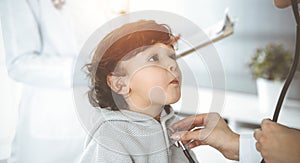 Woman-doctor examining a child patient by stethoscope in sunny clinik. Cute arab toddler at physician appointment