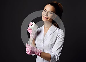 Woman doctor gynecologist reproductologist in pink latex gloves and uniform standing and holding medical bandage