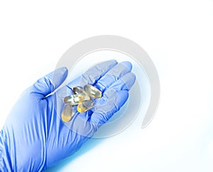 Woman doctor hand in a blue gloves holding gel capsules. Medical, pharmacy and healthcare concept. Copy space