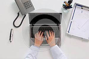 Woman doctor hands typing on laptop at clinic