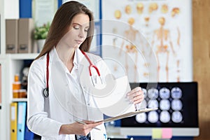 Woman doctor holding clipboard with patient history in clinic