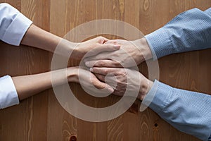 Woman doctor holding hands of senior man, loseup top view