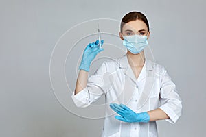 Woman doctor holding syringe on gray background.