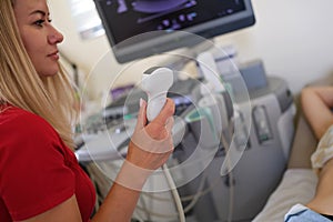 Woman doctor holding ultrasound transducer and examining female patient