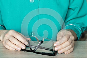 woman doctor holds in hands protective medical glasses at the desks in the doctor& x27;s office