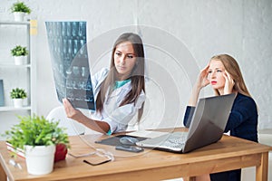 Woman doctor in hospital looking at x-ray film healthcare, roentgen, people and medicine concept.