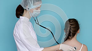 Woman doctor listening to breathe of child girl with phonendoscope