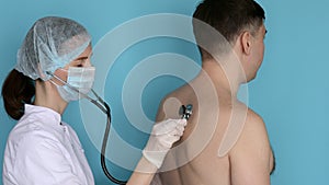Woman doctor listening to breathe of man with phonendoscope