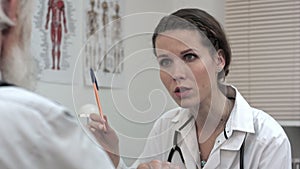 Woman doctor listening to senior patient talking.