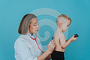 Woman doctor listens with a stethoscope to the lungs of a little boy