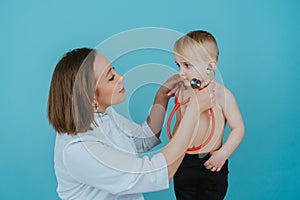 Woman doctor listens with a stethoscope to the lungs of a little boy