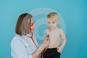 Woman doctor listens with a stethoscope to the lungs of a little boy