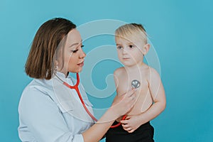 Woman doctor listens with a stethoscope to the lungs of a little boy