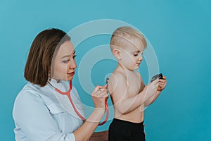 Woman doctor listens with a stethoscope to the lungs of a little boy