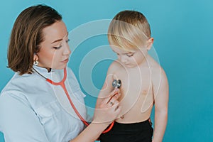 Woman doctor listens with a stethoscope to the lungs of a little boy