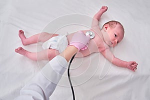 Woman doctor listens with a stethoscope to a newborn baby. Nurse checks the child health with a stethoscope