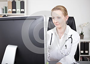 Woman Doctor Looking at Computer Monitor Seriously