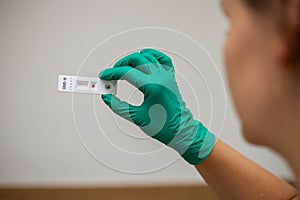 Woman doctor looking at Covid-19 rapid test wearing green latex gloves photo