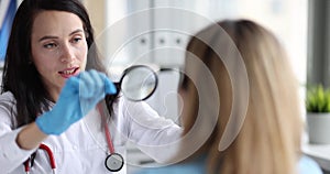 Woman doctor looking at patient face through magnifying glass 4k movie slow motion