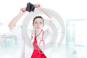 Woman doctor looking shocked by her empty wallet