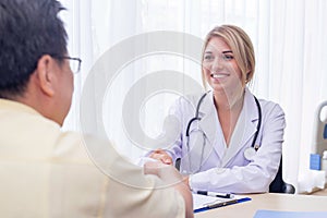 Woman doctor and male patient discussing handshake After the conclusion, the treatment at the desk at hospital